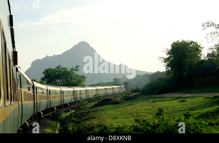 Un train des chemins de fer indiens (Garib rath) une courbe de manoeuvres dans les Ghâts occidentaux, Tamil Nadu, Inde. Banque D'Images