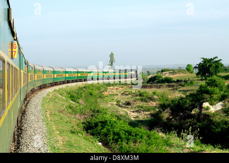 Un train des chemins de fer indiens (Garib rath) une courbe de manoeuvres dans les Ghâts occidentaux, Tamil Nadu, Inde. Banque D'Images