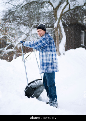 L'homme enlever la neige avec une pelle à partir de la grande cour arrière Banque D'Images