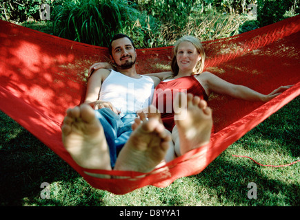 Un jeune couple assis dans un hamac rouge. Banque D'Images