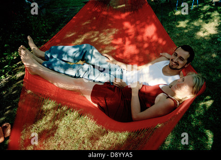 Un jeune couple assis dans un hamac rouge. Banque D'Images