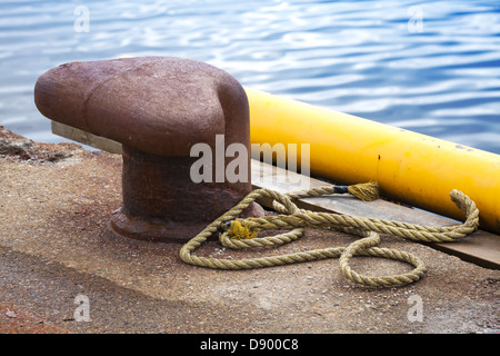 Ancienne borne d'amarrage rouillées avec corde de marine sur les piliers de béton Banque D'Images