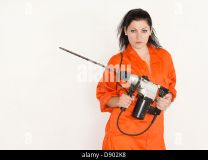 Autorités convaincu Jeune femme debout tenant une maçonnerie sans fil perceuse électrique dans ses mains avec un peu attaché Banque D'Images