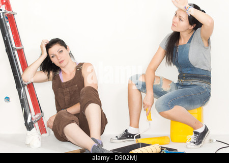 Deux soeurs fatigué et la décoration et peinture assis aux côtés d'un escabeau Banque D'Images