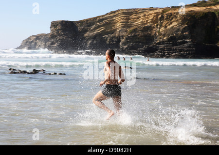 Un homme court dans la mer. Banque D'Images