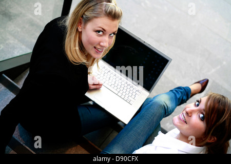 Deux femmes assises sur l'escalier avec un ordinateur portable. Banque D'Images