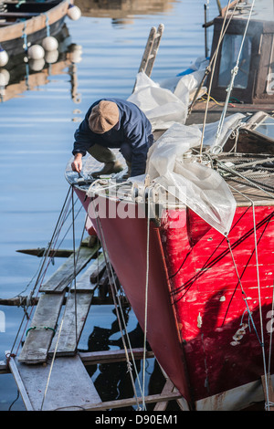 L'homme travaillant sur le bateau à Corrie sur l'île d'Arran en Écosse. Banque D'Images