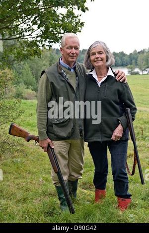 Senior couple holding rifle, smiling Banque D'Images