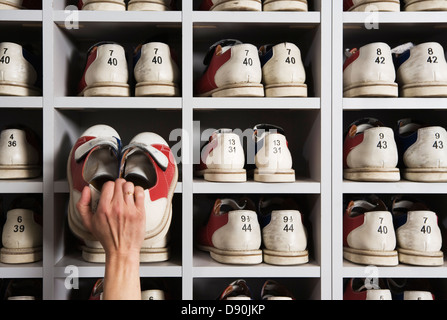 Chaussures à la main sur des étagères dans un bowling. Banque D'Images