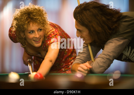 Une femme jouant au billard de poche et de parler à un(e) ami(e). Banque D'Images