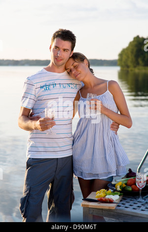 Couple standing by lake holding wine glasses Banque D'Images