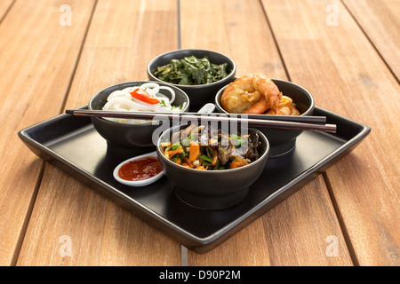 Un plat traditionnel chinois sur une plaque carrée en noir bols avec crevettes, nouilles de riz, kale (chou vert) et de légumes. Banque D'Images