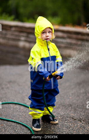 Boy holding tuyau de jardin Banque D'Images