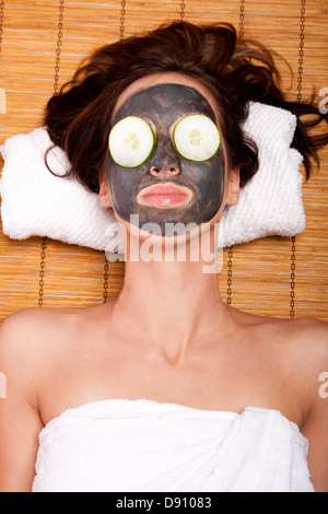 Femme avec un soin de beauté visage masque et pose de concombre sur bambou à spa. Banque D'Images
