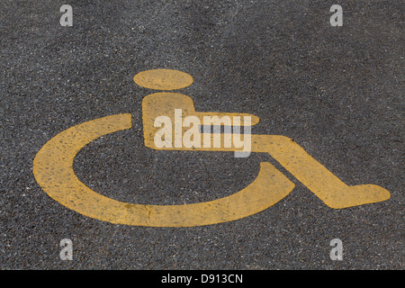 Panneau routier handicap fauteuil roulant jaune peint sur un trottoir Banque D'Images