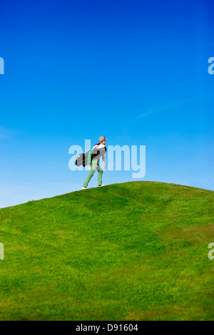 Homme marchant jusqu'à la colline avec sac de golf Banque D'Images