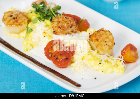 Saffron risotto aux pétoncles grillés et sauce aux tomates cerises Banque D'Images