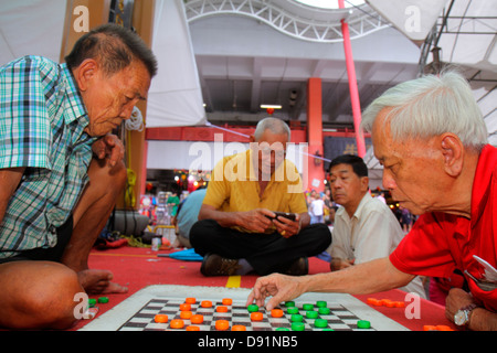 Singapore Chinatown,Asian man men male,jouer,dames,brouillons,jeu de société,caractères hanzi,vérification,smartphone,téléphones,vérifier le texte de lecture Banque D'Images