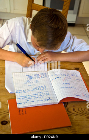 Treize garçon de 13 ans faire des mathématiques devoirs sur table de cuisine Banque D'Images