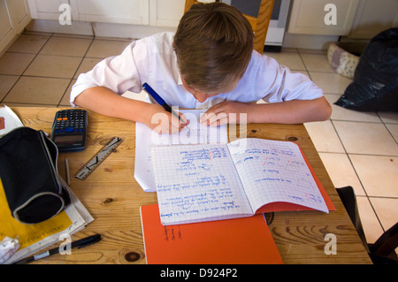 Treize garçon de 13 ans faire des mathématiques devoirs sur table de cuisine Banque D'Images