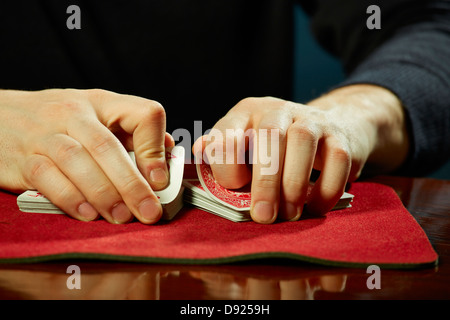 Magicien mâle mains effectuant les cartes à jouer astuce casino sur table. Banque D'Images