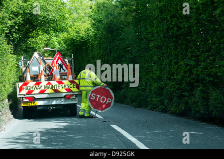 L'entretien routier travailleur ayant un panneau d'arrêt de la circulation. Devon, Angleterre Banque D'Images