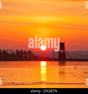 Tour des chasseurs près de l'étang en hiver au lever du soleil Banque D'Images