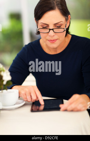 Belle femme d'âge moyen à l'aide de tablet computer at home Banque D'Images