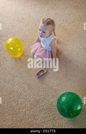 Petite fille entre deux ballons que ses chaussures de ballet se trouve sur le sol Banque D'Images