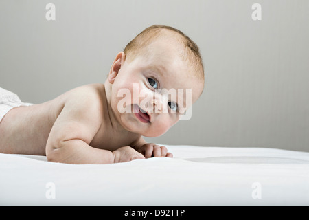 Studio shot of happy baby lying on bed Banque D'Images