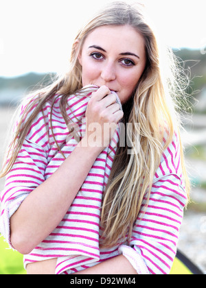 Une jeune femme couvrant sa bouche avec sa chemise et souriant joyeusement Banque D'Images