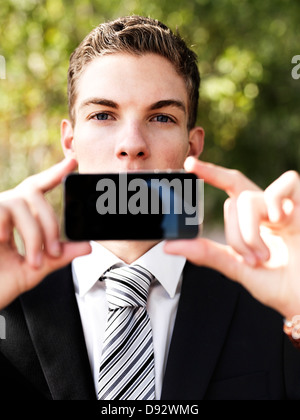 Un jeune businessman holding his smart phone jusqu'en face de sa bouche Banque D'Images