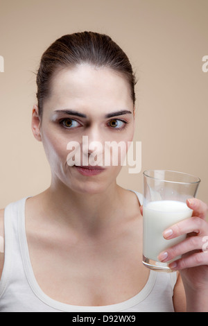 Une jeune femme faisant un visage après avoir pris un verre de lait Banque D'Images