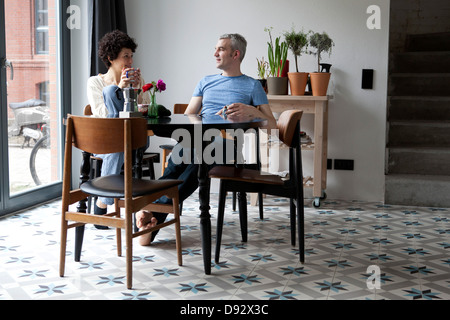 Un couple d'âges mixtes de la hanche gaie appréciant leur petit-déjeuner ensemble dans la salle à manger Banque D'Images