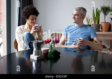 Un couple d'âges mixtes de la hanche gaie appréciant leur petit-déjeuner ensemble dans la salle à manger Banque D'Images