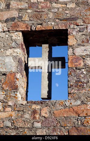 Une croix dans une fenêtre ouverte du mur de pierre d'une église Banque D'Images