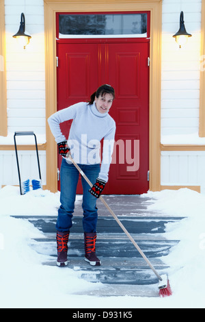 Femme enlever la neige de marches Banque D'Images