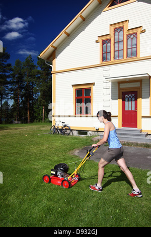 Young woman mowing lawn Banque D'Images