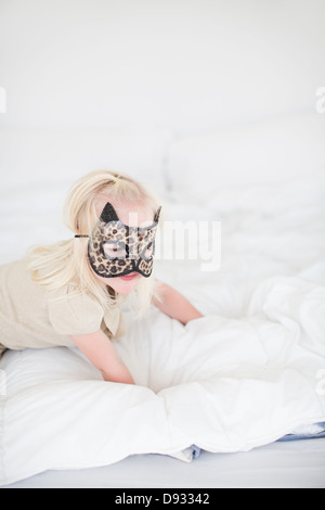 Cat Girl wearing mask ramper sur le lit Banque D'Images