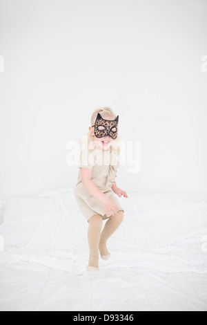 Masque de chat girl jumping on bed Banque D'Images