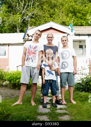 Mère et trois fils debout devant des week-end cottage Banque D'Images