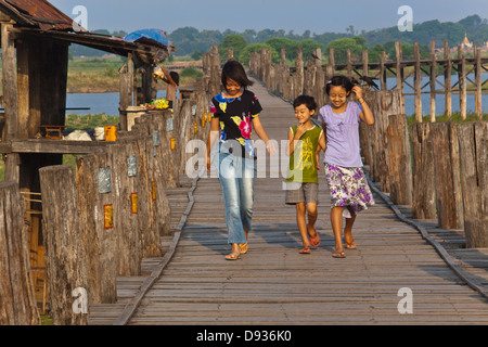 Les Birmans utilisent le pont en teck U BEINS de commuer en face du lac Taungthaman au lever du soleil - AMARAPURA, MYANMAR Banque D'Images