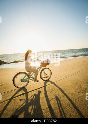 Mixed Race woman riding bicycle on beach Banque D'Images