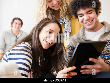 Des amis à l'aide de tablet computer in living room Banque D'Images