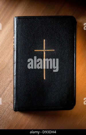 Relié en cuir noir avec bords dorés bible prières pages et croix en or sur la couverture posée sur la surface en bois Banque D'Images