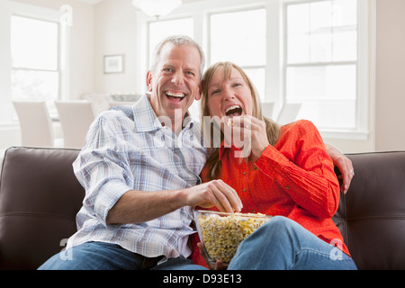 Caucasian couple eating popcorn sur canapé Banque D'Images