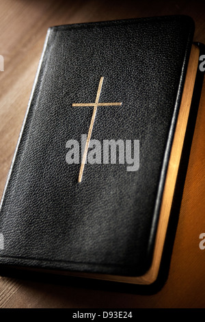 Relié en cuir noir avec bords dorés bible prières pages et croix en or sur la couverture posée sur la surface en bois Banque D'Images