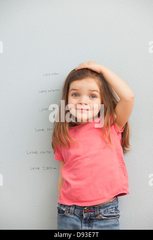 Caucasian girl measuring her hauteur sur mur Banque D'Images