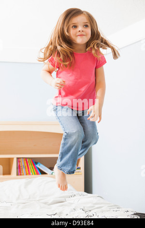 Caucasian girl jumping on bed Banque D'Images