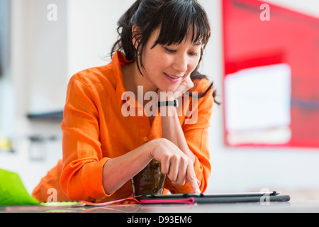 Asian woman using tablet computer in kitchen Banque D'Images